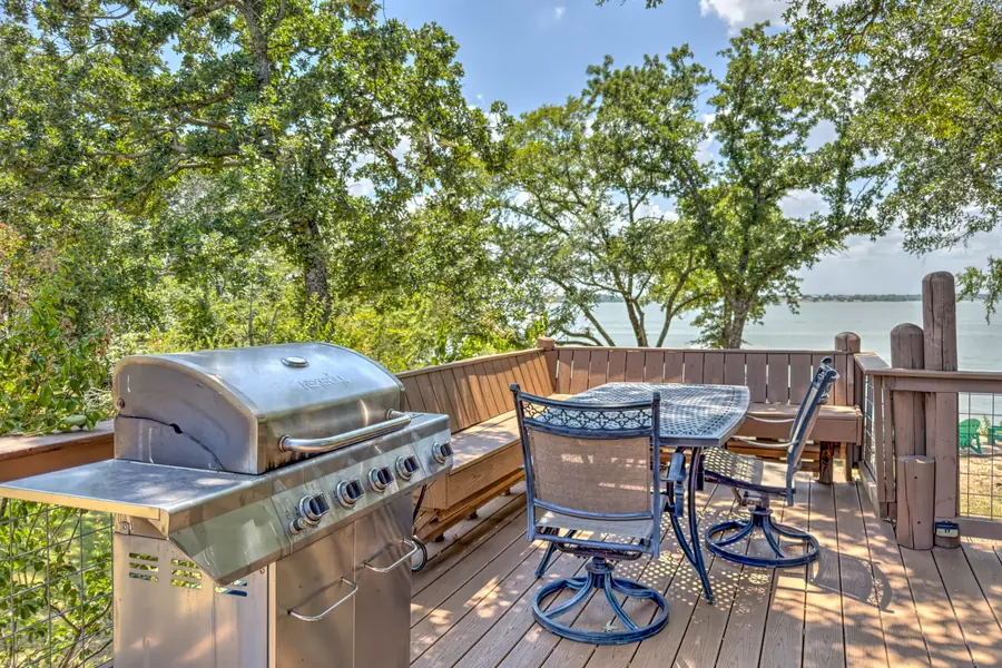 Deck with a gas grill and outdoor dining table overlooking the lake