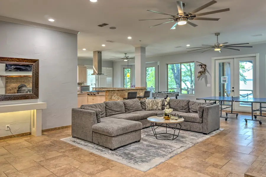 Open living room with a large grey sectional, ceiling fans and lake-facing windows