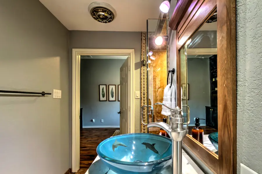 Blue glass vessel sink with a framed mirror