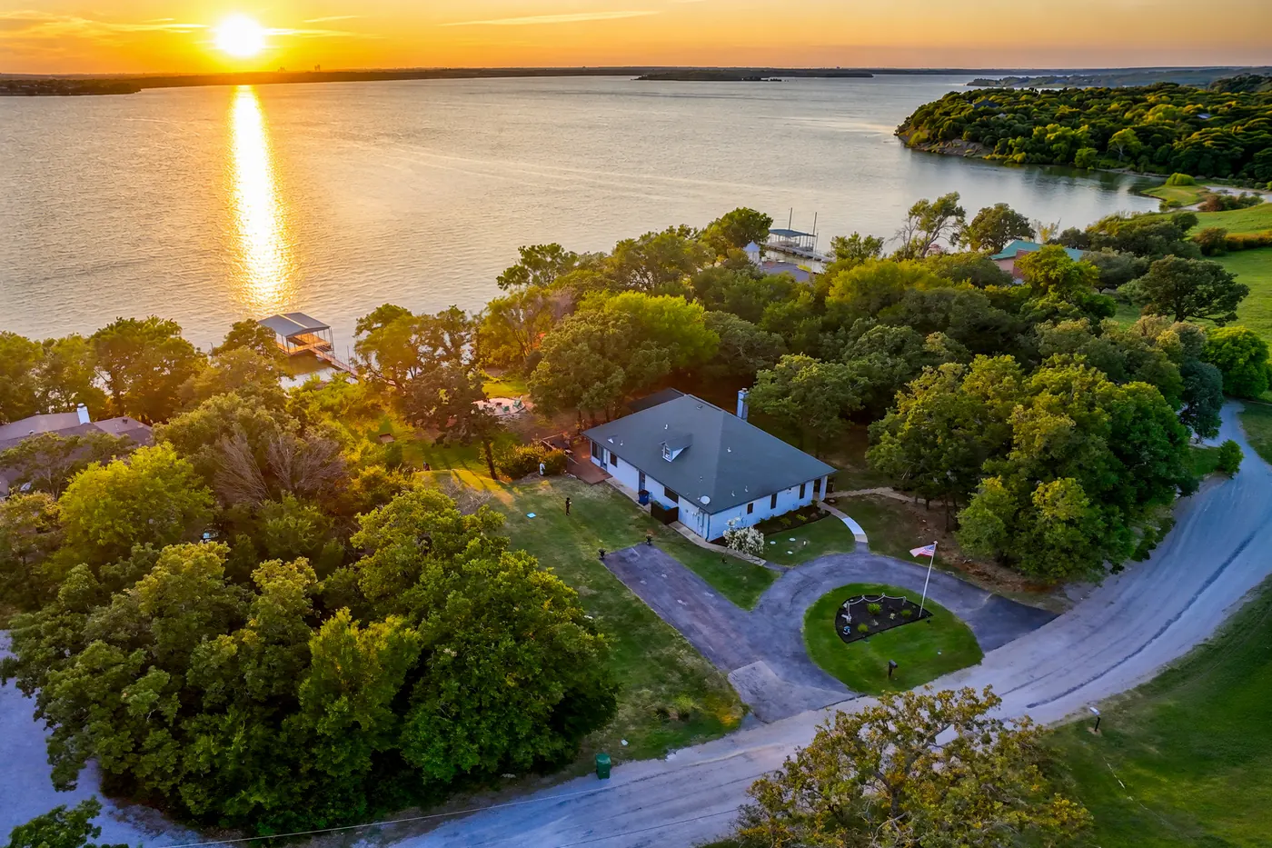 Aerial view of Lakefront Haven at sunset, the sun low over the lake behind the house